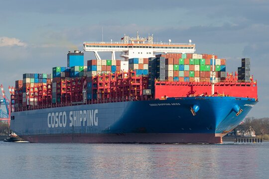 Large cargo vessel, "Cosco shipping," is navigating through the blue waters of the Port of Hamburg