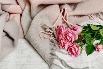 Beautiful soft pink blanket and bouquet of roses on it.