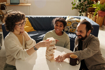 Happy family playing board game together with adopted child while sitting in the living room at home