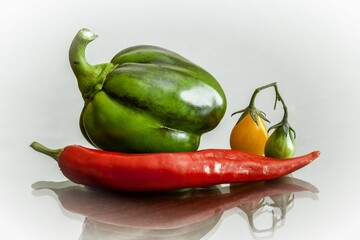 Closeup of some vegetables on a reflecting surface with a white background
