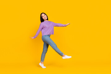 Full length photo of funky carefree lady dressed purple shirt walking empty space isolated yellow color background
