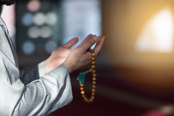 Hand of male muslim praying with mosque interior background during ramadan