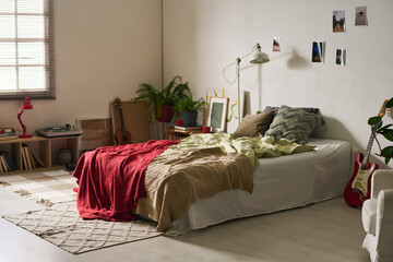 Horizontal image of bright teenage room with big comfortable bed