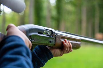 Skeet Shooting .Man shooting at target on an outdoor shooting range at sunny day, training alone,...