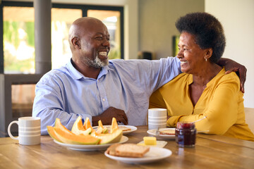 Fototapeta na wymiar Senior Couple At Home Enjoying Breakfast Around Table Together