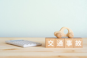 交通事故と書かれたブロックと車のおもちゃと電卓
