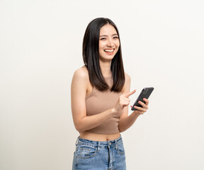 Fototapeta premium Pretty young asian woman using smartphone standing on isolated white background. Excited Beautiful young asian shopping online payment with mobile phone. Playing game on smartphone