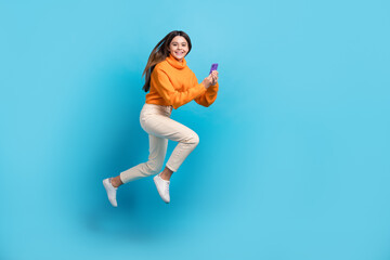 Fototapeta na wymiar Full body photo of active excited person jump rush use smart phone empty space isolated on blue color background