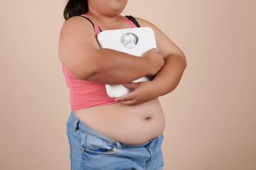 Overweight woman posing with holding weighing machine to exercise to lose weight stand isolated on white background. fitness concept.  Dieting and slimming theme.
