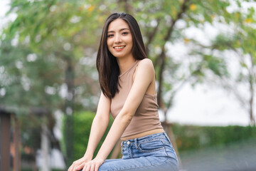 Fototapeta premium Happy feeling of Beautiful Young Woman smiling outdoor in sunlight. Pretty attractive face of female and beautiful smile. She is positive thinking and successful.