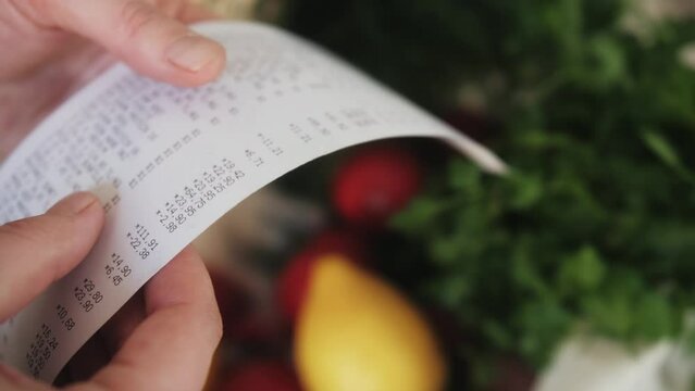 The buyer holds a purchase receipt in hands, checks purchases and prices.