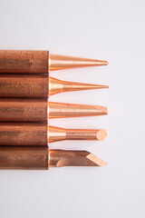 Close up of soldering tips on glass table, silver background with equipment for soldering iron