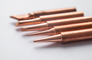 Close up of soldering tips on glass table, silver background with equipment for soldering iron