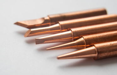 Close up of soldering tips on glass table, silver background with equipment for soldering iron