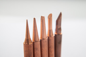 Close up of soldering tips on glass table, silver background with equipment for soldering iron