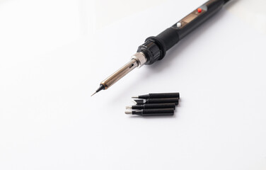 Close up of soldering tips on glass table, silver background with equipment for soldering iron