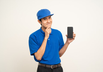 Asian man in blue uniform standing holding smartphone on isolated white background. Male service worker with cell phone. Delivery courier shipping service