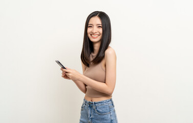 Naklejka premium Pretty young asian woman using smartphone standing on isolated white background. Excited Beautiful young asian shopping online payment with mobile phone. Playing game on smartphone