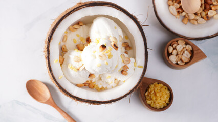 Coconut ice cream topped with roasted peanuts in a coconut shell macro shot. (spot focus)