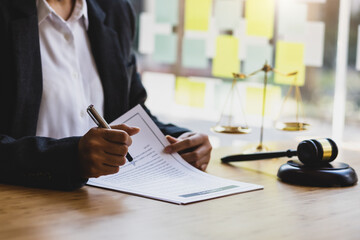 Female lawyer working in the office reading documents and signing legal agreement contracts.