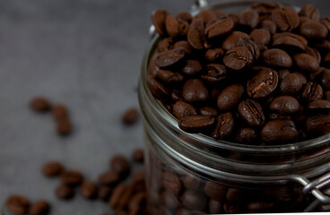 Roasted coffee beans in a glass jar, close up. Copy space