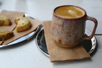 Coffee mug full of cortado coffee shot on white background next to cookies.
