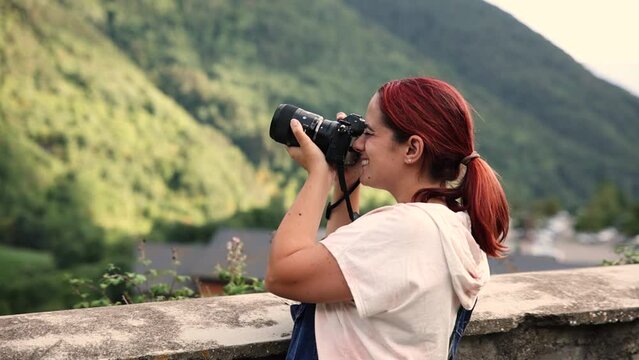 Young caucasian woman taking pictures with a professional camera in a beautiful natural environment between mountains. Enjoy summer holiday in nature and rural tourism concept