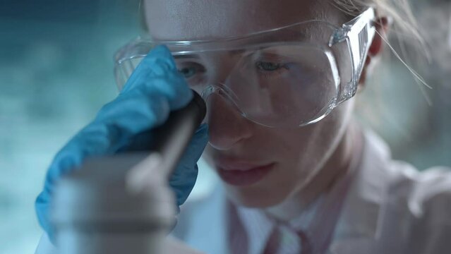 Medical science laboratory. A microbiologist wearing glasses is looking under microscope analyzing sample. Scientist pharmacist working with forensic. Genetic dna research and pharmaceutics concept