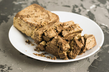Delicious halva with cocoa on a white plate on a light gray concrete background