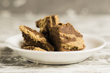 Delicious halva with cocoa on a white plate on a light gray concrete background