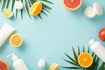 Fototapeta na wymiar Citrus summer beauty concept. Top view flat lay of mock up cream bottles, jars, serum, pipette with orange, grapefruit, lemon, flower on blue background with empty space for text. Stylish and juicy