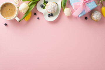 Celebrate Mother's Day with trendy table setting concept. Top view flat lay of plates with mouth-watering cupcakes, presents, coffee, tulips on pastel pink background with empty space for message
