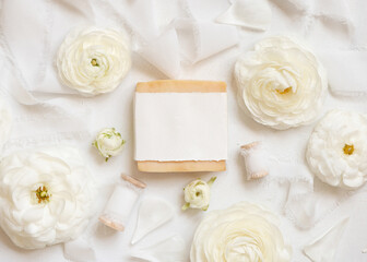 Obraz na płótnie Canvas Handmade soap bar with blank label near cream roses and white ribbons top view, mockup