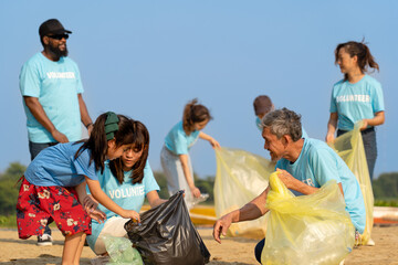 group of diverse volunteers charitable working together to clean up river beach, senior adult and girls picking trash into garbage bags separating reused plastic for recycling waste management