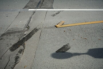 Abgelöste gelbe Fahrbahnmarkierungsfolie auf grauem Asphalt bei Sonnenschein auf einer Baustelle...