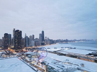 Fototapeta na wymiar Majestic view of Chicago with a ferris wheel in the foreground and snow-capped buildings