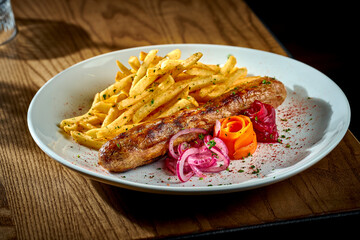 Bavarian meat sausage with a side dish of french fries, onions in a plate on a wooden background. bratwurst