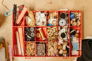 Open box with various sewing accessories, such as buttons, ribbons, and thread - obrazy, fototapety, plakaty
