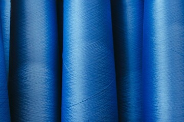 Closeup image of two blue thread spools, arranged in a vertical pattern