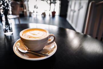 Coffee cappuccino in cup on wooden table in cafe