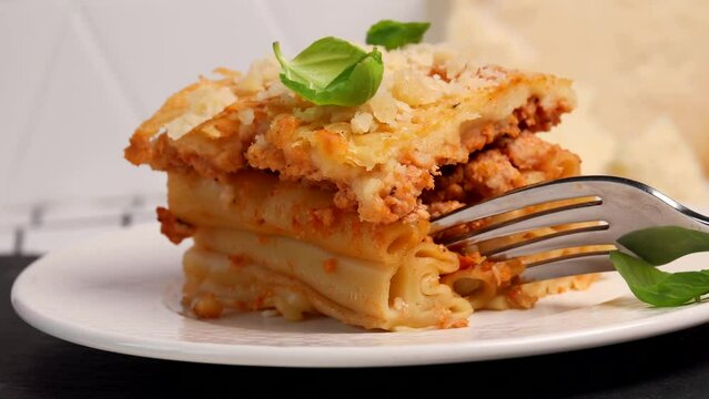 Greek Pastitsio is a Greek version of Lasagna. layer of tubular pasta beef ragu and béchamel sauce. Pasta with cheese and basil leaf on a plate