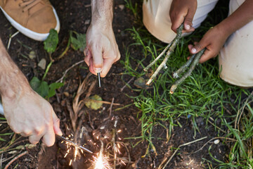 Top view closeup of father and son starting campfire together while hiking in forest