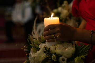 Woman in a red dress holding a lit candle in her hand in the church
