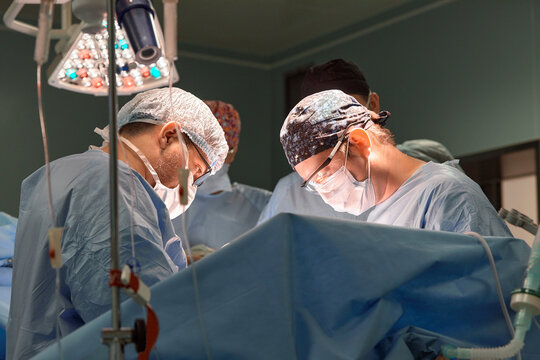 Surgeon face in operating room, stressful operation, surgeon performs operation in modern operating room with activity life support devices and light lamps, life saving, inoperable sarcoma.