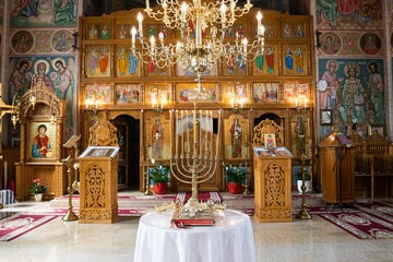 Fototapeta na wymiar Golden chandelier inside an Orthodox church with saints' icons on the walls.