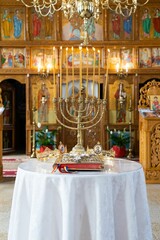 Vertical shot of a golden candle holder with two crowns inside an Orthodox church. Orthodox wedding.