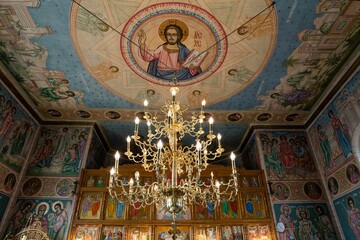 Fototapeta na wymiar Golden chandelier inside an Orthodox church with saints' icons on the walls.