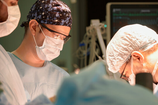 Surgeon face in operating room, stressful operation, surgeon performs operation in modern operating room with activity life support devices and light lamps, life saving, inoperable sarcoma.