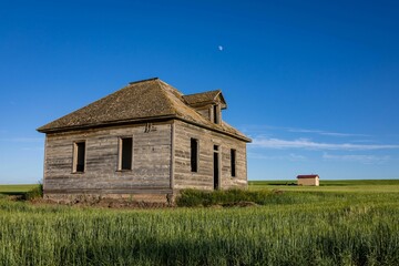 Derelict, abandoned house in an open grassland area on a sunny day