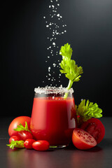 Sea salt is poured into a glass of tomato juice with celery.